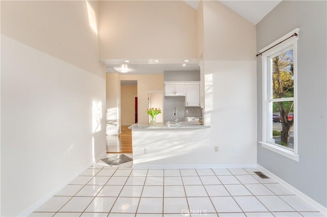 interior space with light tile patterned floors, visible vents, a peninsula, light countertops, and white cabinets