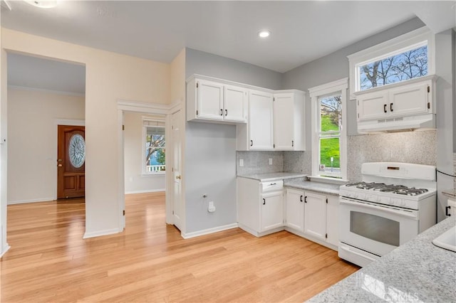 kitchen with under cabinet range hood, backsplash, white cabinetry, light wood finished floors, and white range with gas stovetop