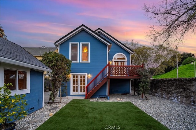 back of house at dusk featuring stairway, french doors, a lawn, and a wooden deck