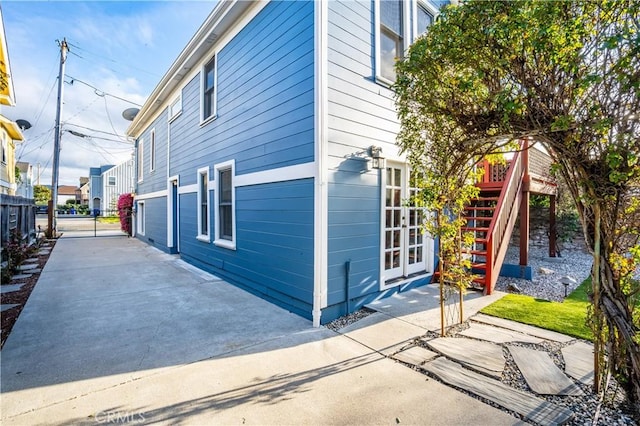 view of property exterior featuring french doors, stairs, and fence