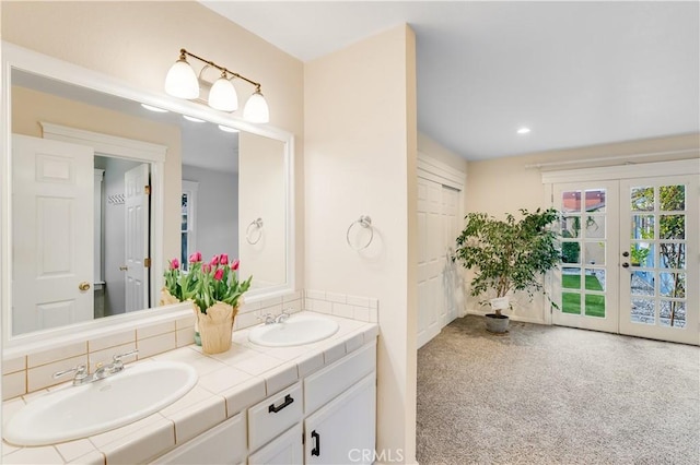 bathroom with double vanity, french doors, tasteful backsplash, and a sink