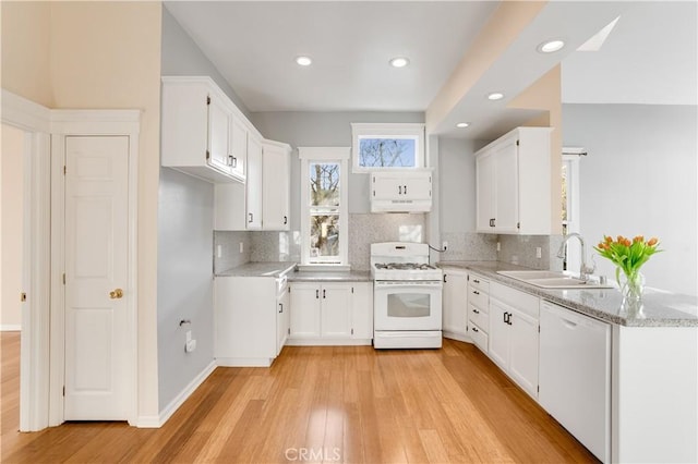 kitchen featuring white appliances, light wood-style flooring, a sink, decorative backsplash, and white cabinetry