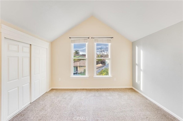 unfurnished bedroom with a closet, carpet flooring, baseboards, and vaulted ceiling