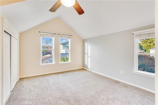 unfurnished bedroom featuring lofted ceiling, multiple windows, a closet, and light carpet