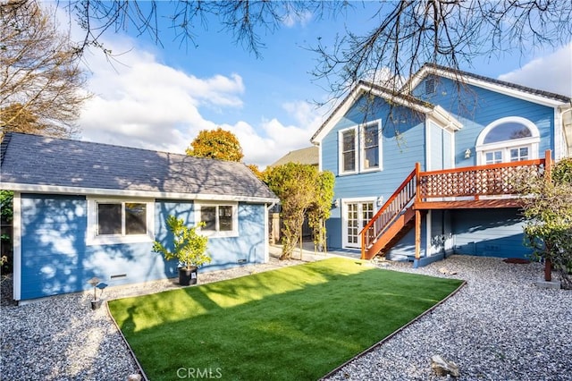 back of property with a deck, stairway, a lawn, and a shingled roof