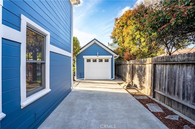 detached garage with concrete driveway and fence