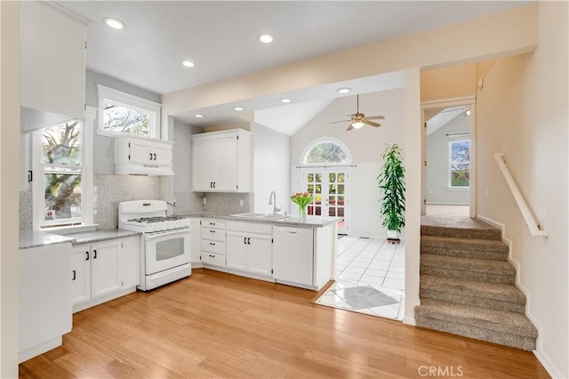 kitchen with a peninsula, white cabinets, white appliances, a ceiling fan, and a sink