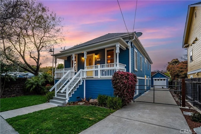 view of front of property featuring fence, a porch, a yard, an outdoor structure, and driveway