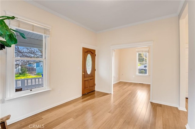 foyer entrance with crown molding, light wood-style flooring, and baseboards