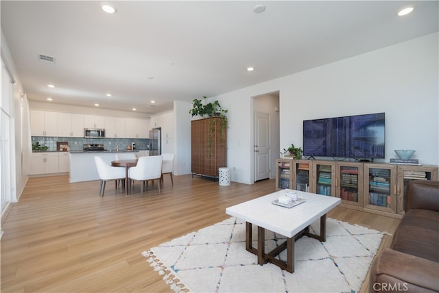 living area with light wood-style flooring, recessed lighting, and visible vents