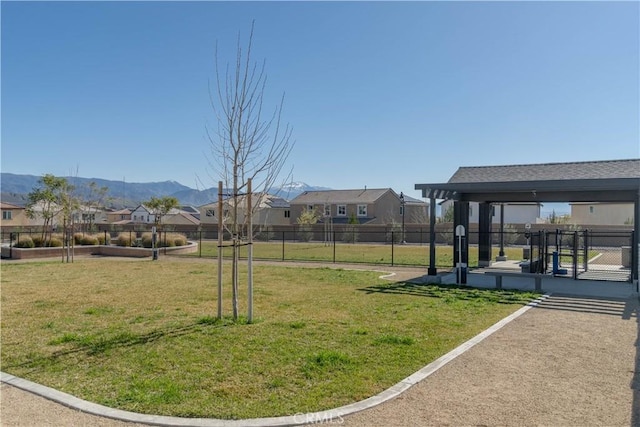 view of yard featuring a mountain view, a residential view, and fence