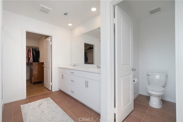 bathroom featuring a walk in closet, tile patterned floors, visible vents, and a sink