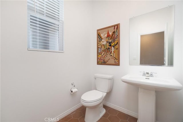 bathroom featuring tile patterned flooring, toilet, baseboards, and a sink