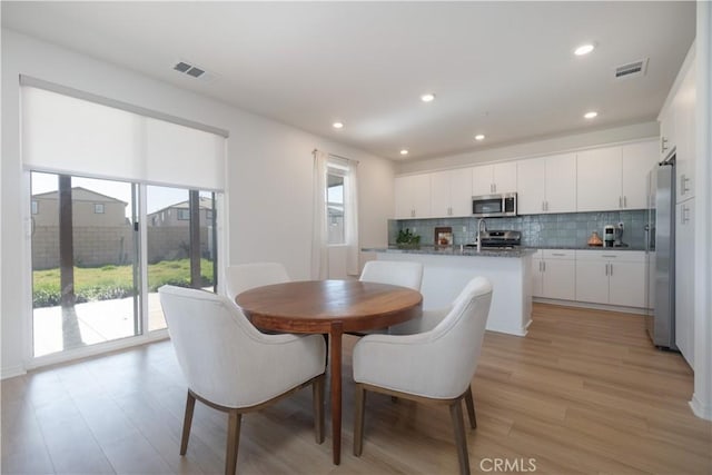 dining area with light wood-type flooring, visible vents, and recessed lighting