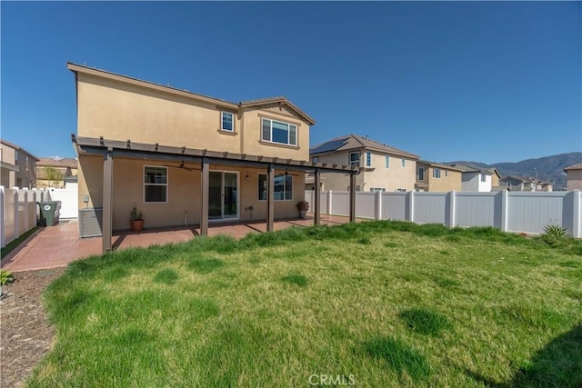 rear view of property featuring a yard, a patio area, a fenced backyard, and stucco siding