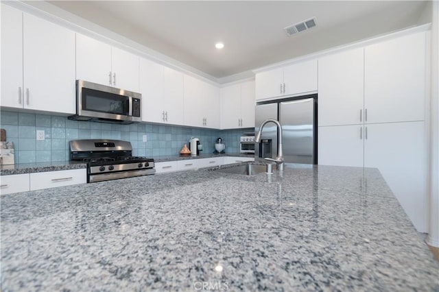 kitchen with stainless steel appliances, light stone countertops, visible vents, and decorative backsplash