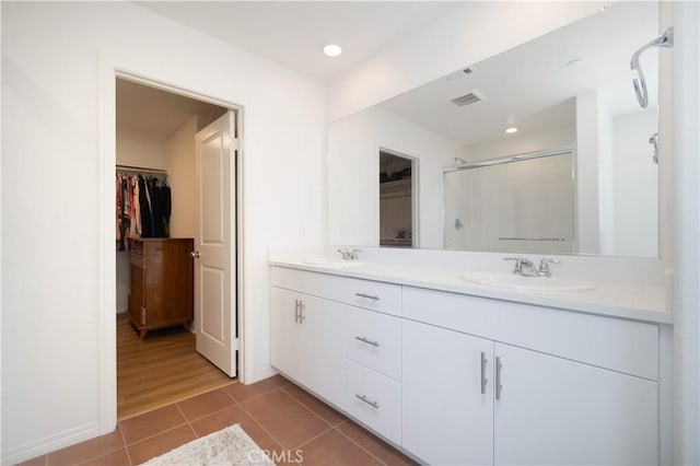 full bathroom featuring tile patterned flooring, a shower stall, a walk in closet, and a sink