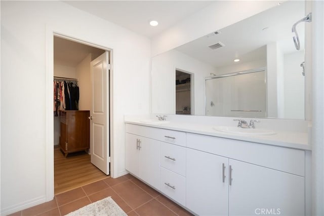 full bathroom featuring a sink, a spacious closet, tile patterned floors, and a stall shower