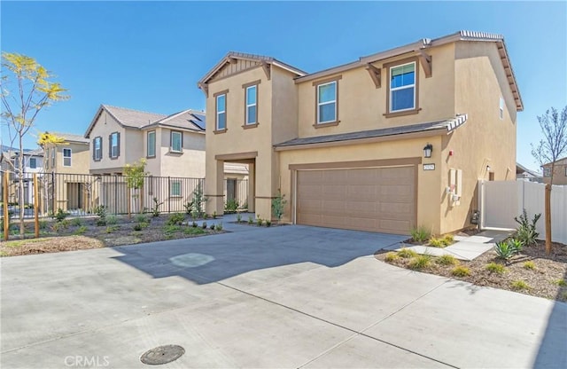 view of front of home featuring stucco siding, fence, a residential view, concrete driveway, and a garage