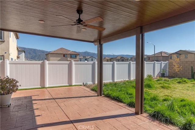 view of patio featuring a mountain view, a ceiling fan, a residential view, and a fenced backyard