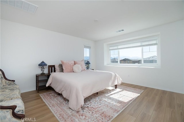 bedroom featuring light wood-type flooring, baseboards, and visible vents