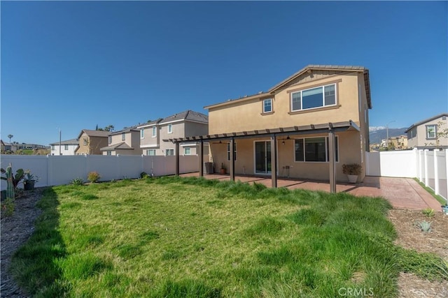 rear view of property featuring a patio area, stucco siding, a lawn, and a fenced backyard