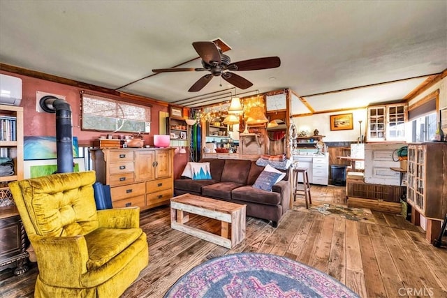 living area with a wood stove, an AC wall unit, hardwood / wood-style floors, and a ceiling fan