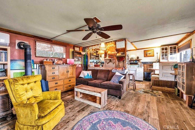 living area featuring a wood stove, hardwood / wood-style flooring, a ceiling fan, and a healthy amount of sunlight