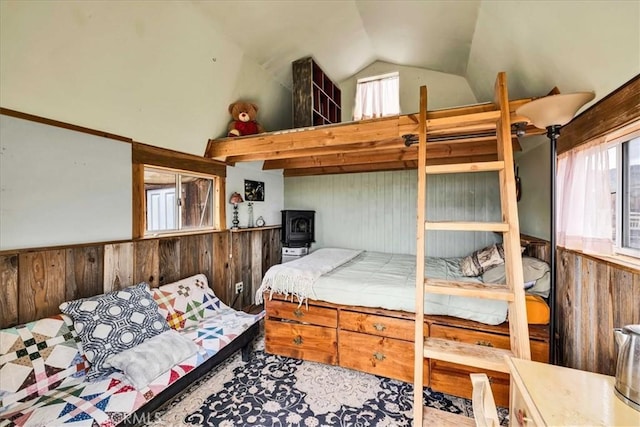 bedroom with lofted ceiling, wooden walls, and a wainscoted wall