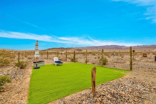 view of yard with a rural view, fence, and a mountain view