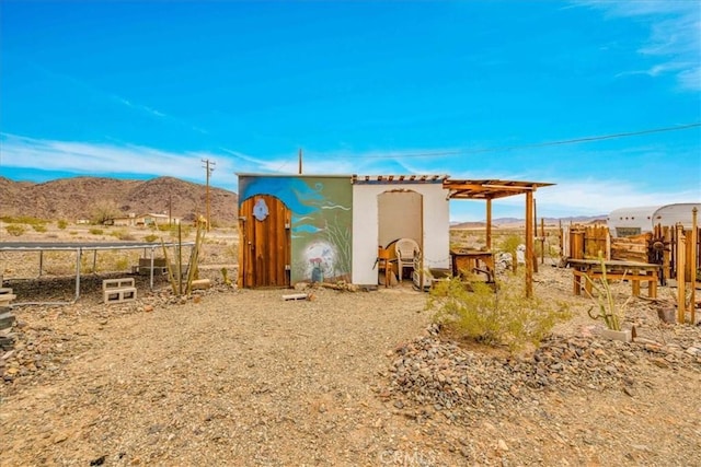 view of outdoor structure with an outbuilding, fence, and a mountain view