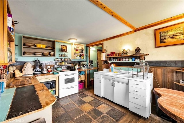 kitchen with white electric range oven, open shelves, white cabinets, a sink, and wainscoting