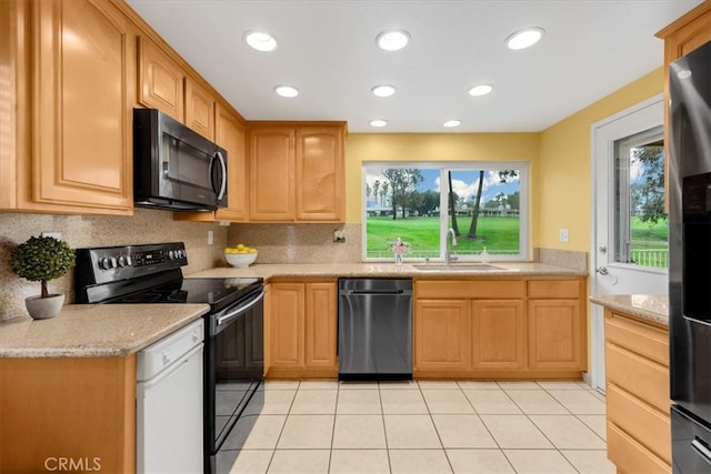 kitchen with a sink, light tile patterned flooring, black appliances, and tasteful backsplash