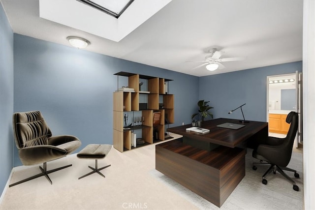 office with a skylight, light colored carpet, and ceiling fan