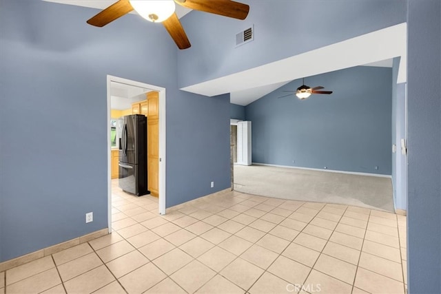 empty room with light tile patterned floors, a ceiling fan, visible vents, high vaulted ceiling, and light carpet