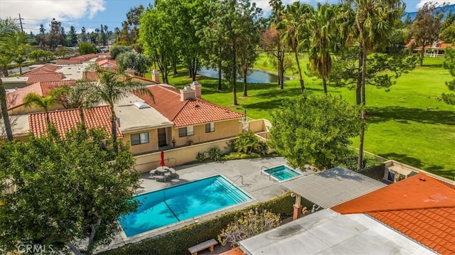 community pool with a yard, a water view, and a patio