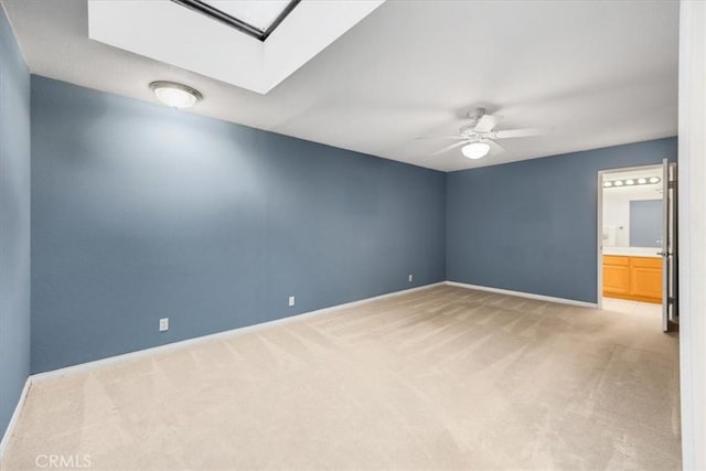 spare room with ceiling fan, baseboards, light carpet, and a skylight