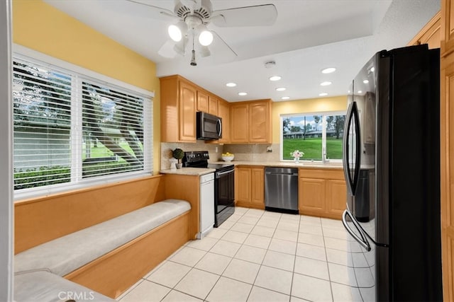 kitchen featuring a wealth of natural light, black appliances, backsplash, light countertops, and light tile patterned floors