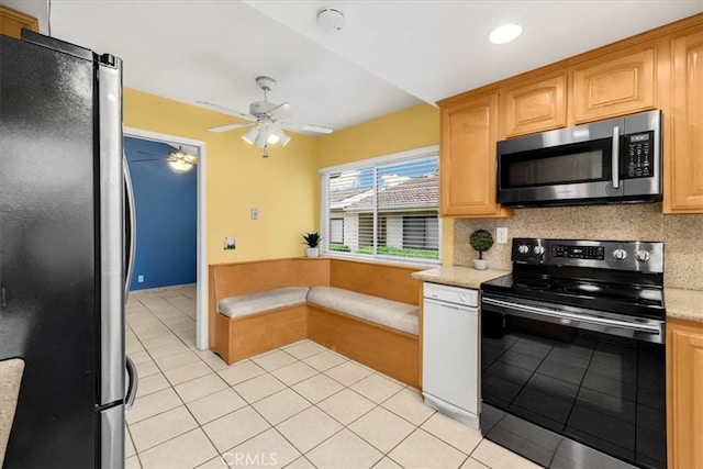 kitchen with stainless steel appliances, decorative backsplash, light tile patterned flooring, and a ceiling fan