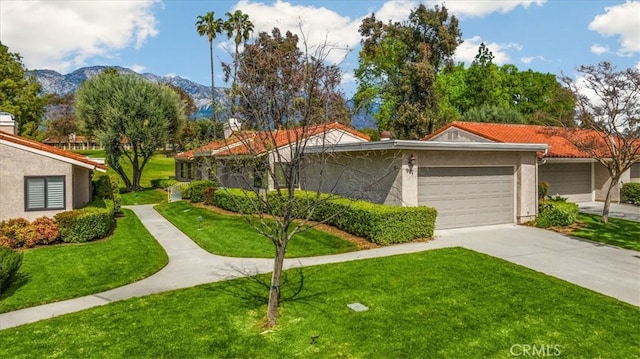 view of front facade with a garage, a mountain view, driveway, and a front lawn