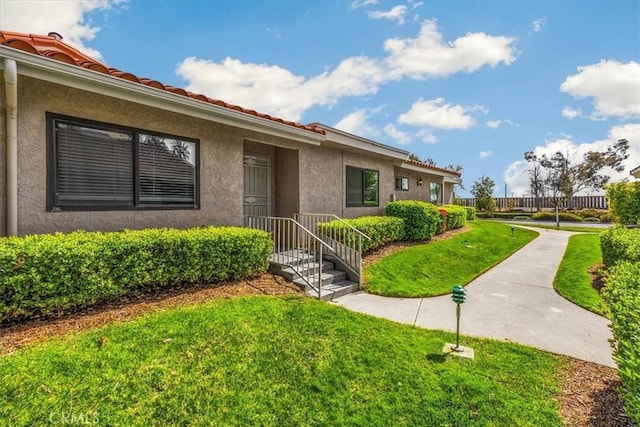 entrance to property with stucco siding and a yard