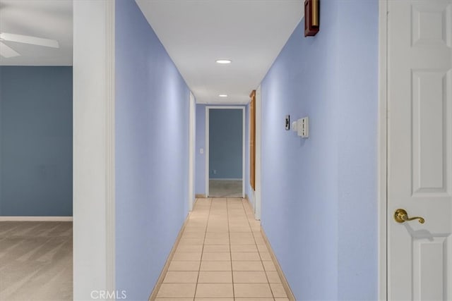 hall with light tile patterned flooring and baseboards