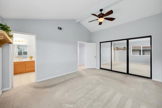 unfurnished bedroom featuring baseboards, visible vents, ensuite bath, beam ceiling, and light carpet