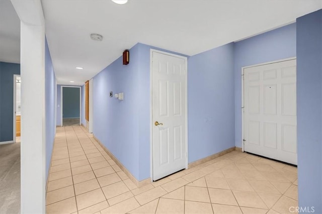 corridor featuring light tile patterned floors and baseboards