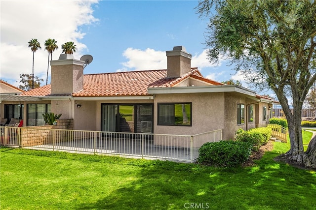 rear view of house with a tile roof, stucco siding, a yard, and a chimney