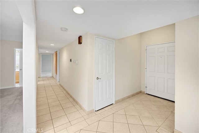 hallway featuring light tile patterned floors, baseboards, and recessed lighting
