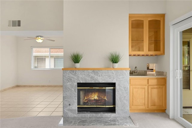 details with ceiling fan, visible vents, a fireplace with flush hearth, a sink, and baseboards