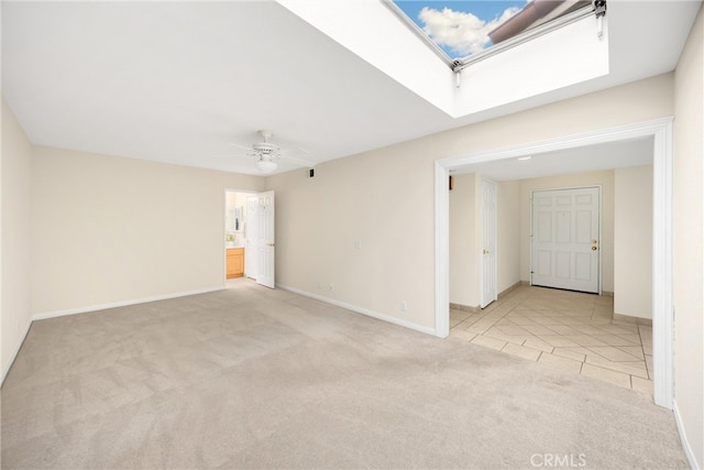 empty room with light tile patterned floors, baseboards, a ceiling fan, and light colored carpet