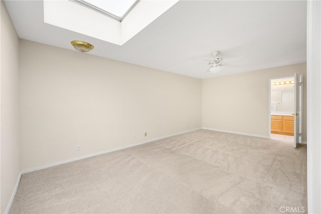 empty room with light colored carpet, baseboards, and a skylight