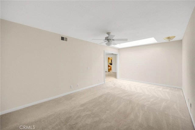 spare room featuring a skylight, ceiling fan, carpet, and visible vents